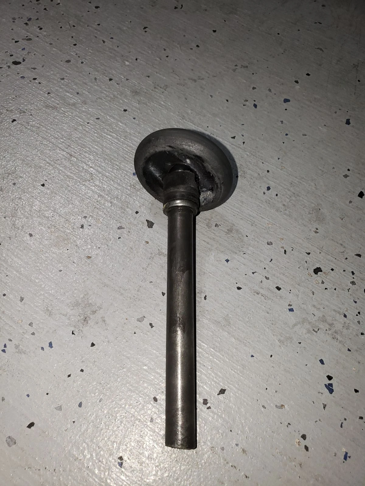 Worn garage door roller with a cracked and chewed wheel lying on a garage floor